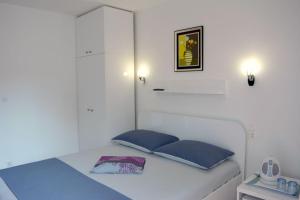 a white bed with blue pillows in a room at Apartmani Ana Juricev Vodice in Vodice