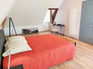 a bedroom with a red bed and a desk at Les Jacquemarts Normands in Belmesnil