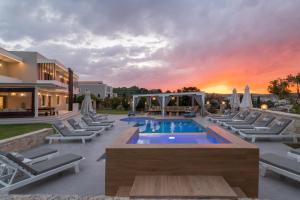 a resort with a pool and lounge chairs at sunset at Elaida Villa, Heaven on Earth, By ThinkVilla in Perama