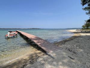 a wooden dock in the water next to a beach at Makis Nest Family Apart-hotel Vourvourou in Vourvourou