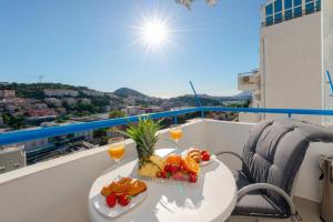 a table with fruit and wine glasses on a balcony at Apartment Sunset free parking in Dubrovnik