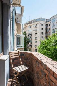 a wooden chair sitting on a brick ledge on a balcony at Classy Apartment Unirii Square in Bucharest