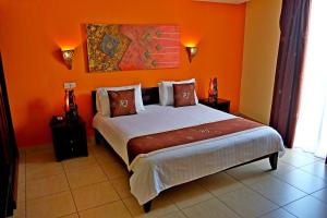 a bedroom with a bed with an orange wall at Hotel Joffre in Toamasina