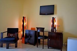 a room with a desk with two chairs and a tv at Hotel Joffre in Toamasina