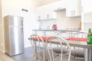eine Küche mit einem Tisch mit Stühlen und einem Kühlschrank in der Unterkunft AL-DOM apartamenty Apartament Olymp 302 in Kołobrzeg