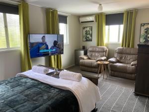 1 dormitorio con 1 cama y TV de pantalla plana en Freshwater BnB, en Hervey Bay