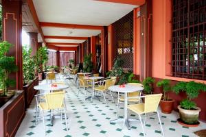 a restaurant with tables and chairs on a tiled floor at Hotel Joffre in Toamasina