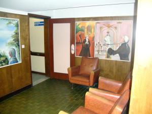 a waiting room with a chair and paintings on the wall at Casa de Retiros N. S. Perpetuo Socorro in Guimarães