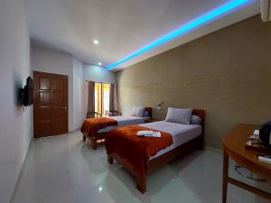 a hotel room with two beds and a blue light at OASIS HOTEL in Ampana