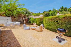 a backyard with chairs and a grill and a hedge at Colina - holiday home with private swimming pool in Moraira in Moraira