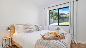 um quarto branco com uma cama com uma bandeja de frutas em Unwind em Gerringong