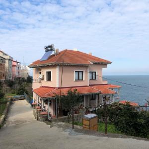 uma casa com um telhado vermelho e o oceano em Villa Laila Trabzon em Trabzon