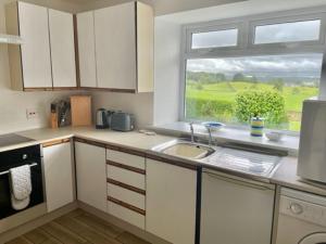 uma cozinha com um lavatório e uma janela em AIRDSIDE COTTAGE em Castle Douglas
