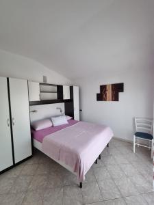 a bedroom with a large bed and a chair at Apartments Jann in Krk