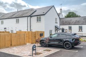 a black car parked in front of a white house at The Bear in Usk