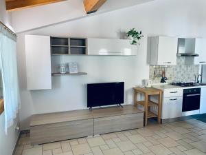 a kitchen with white cabinets and a tv on a counter at Casa Al Piazzol in Alano di Piave