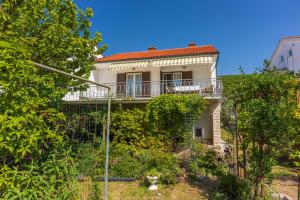 a white house with a balcony and bushes at Apartment Kreso in Punat