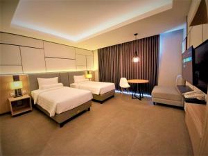 um quarto de hotel com duas camas e uma televisão de ecrã plano em Front One King Hotel Tuban em Tuban