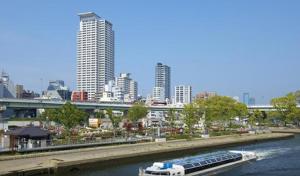 un barco que viaja río abajo en una ciudad en HOTEL LiVEMAX Osaka Yodoyabashi, en Osaka
