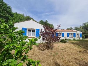 uma casa branca com persianas azuis num quintal em MAISON OROUET PISCINE 4 CHAMBRES em Saint-Jean-de-Monts