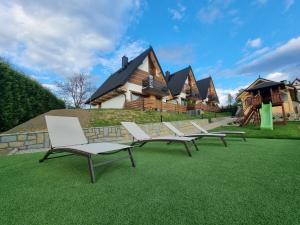 a group of chairs sitting on the grass in front of a house at Tatras Residence in Poronin