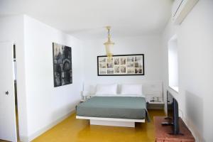 a white bedroom with a bed and a television at HMO Glamping & Suites in Vignanotica in Mattinata