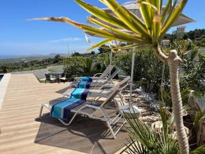 a deck with chairs and a table and a palm tree at Villa Aspria in Rethymno