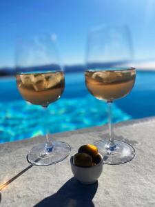 two wine glasses sitting next to a bowl of olives at VILLA AGNES MYKONOS in Mikonos