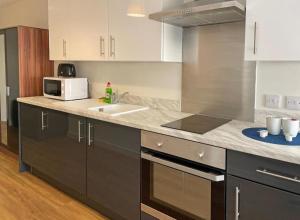a kitchen with a stove top oven and a sink at Granite House Apartments in Liverpool
