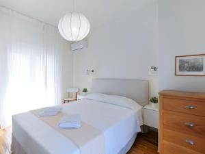 a white bedroom with a white bed and a dresser at Modern Penthouse overlooking Halkis in Chalkida