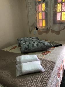 a bedroom with a bed with pillows and a window at Flat Maricá II in Maricá