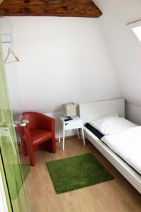 a small bedroom with a bed and a red chair at coLodging Mannheim - private rooms & kitchen in Mannheim