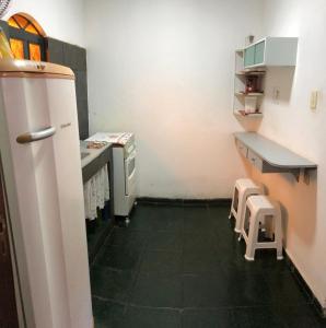 a small kitchen with a refrigerator and two stools at Flat Maricá II in Maricá