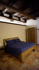 een slaapkamer met een bed met blauwe lakens en houten plafonds bij La Dimora nel Borgo in Ghiffa