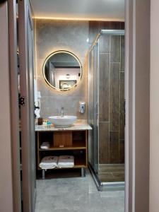 een badkamer met een wastafel en een douche met een spiegel bij Aktas Hotel in Mersin