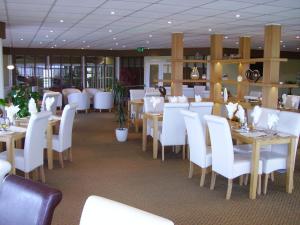 a restaurant with white tables and white chairs at Croyde Bay Hotel or Self Catering in Croyde