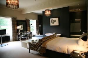 a bedroom with a bed and a tub and a desk at Milsoms Kesgrave Hall in Ipswich