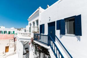 Edificio blanco con persianas azules y balcón en Ryous Mykonos, en Mykonos ciudad