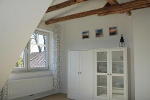 Cette chambre comprend une armoire blanche et une fenêtre. dans l'établissement Elske´s Stuuv, à Krummhörn