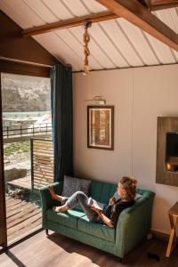 una mujer sentada en un sofá leyendo un libro en Horizon Resort Attabad Lake Hunza, en Hunza