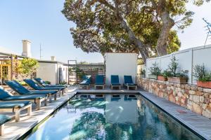 a swimming pool with chairs and a retaining wall at Camps Bay Village - Stone Cottages in Cape Town