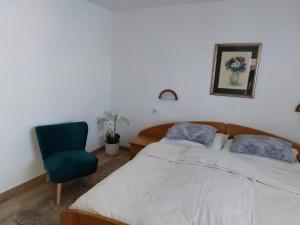 a bedroom with a bed and a green chair at Apartman MARKO in Mali Lošinj