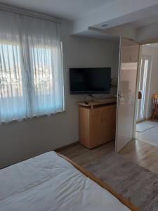a bedroom with a flat screen tv and a bed at Apartman MARKO in Mali Lošinj
