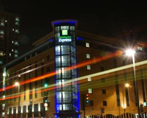 a building with a lit up sign on it at night at Holiday Inn Express London Stratford, an IHG Hotel in London