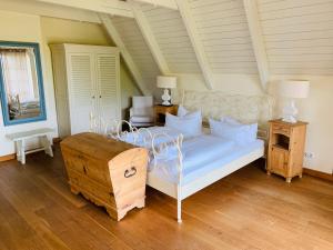 a bedroom with a white bed with a wooden floor at Landhaus am Achterwasser mit Bootssteg in Grüssow