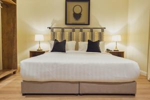 Un dormitorio con una gran cama blanca con dos lámparas. en Malfakum Al Diriyah, en Riad