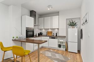 uma cozinha com armários brancos, uma mesa de madeira e cadeiras amarelas em City-Apartment direkt in den Parkanlagen em Bremen