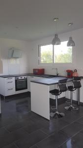 eine Küche mit einer Theke und 2 Barhockern in der Unterkunft Studio à la campagne sans vis à vis in Boulin