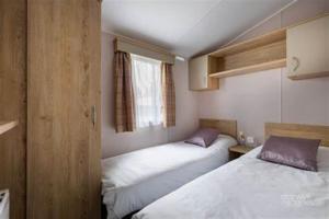 2 Betten in einem kleinen Zimmer mit Fenster in der Unterkunft Edwards Holiday Home in Blackpool