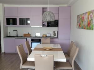 a kitchen with a dining room table and chairs at Sunset Beach Apartment direkt am Strand mit Pool Garten Terasse viel Komfort in Siófok